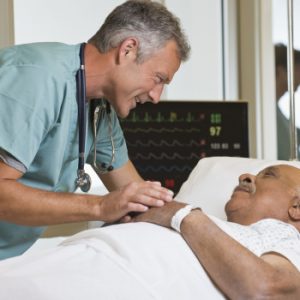 doctor leaning over a man in a hospital bed