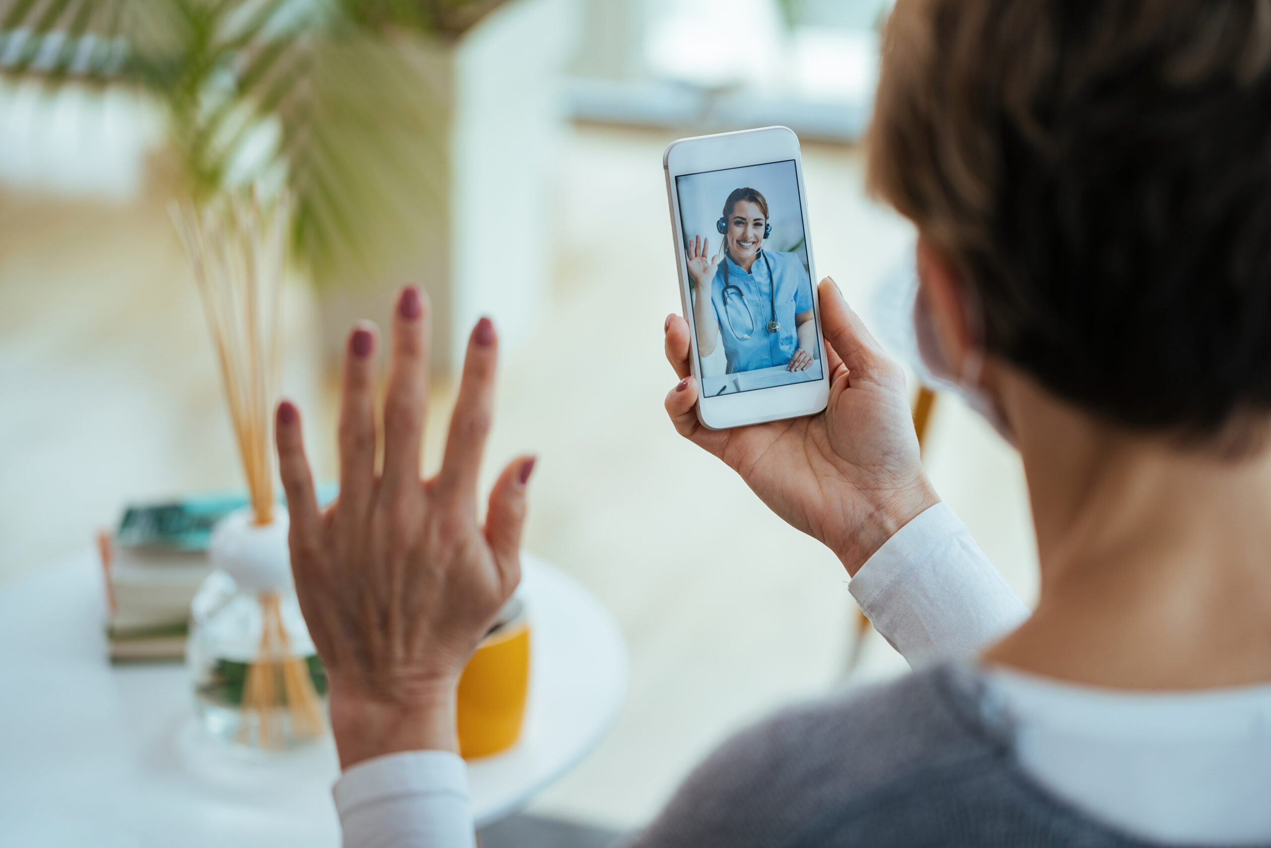 Close-up of woman greeting virtual urgent care from home suing her smartphone